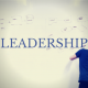 Person writing on a white board. Title - Leadership