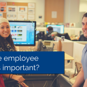 Two employees sitting at their desk, smiling and looking at the camera with title - why are employee benefits important