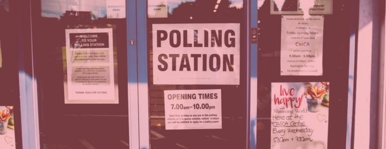 Image of glass doors in front of building. Sign on door says, "polling station"